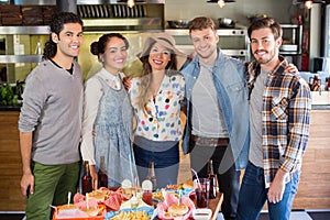 Happy friends standing by food and drink served on table in restaurant