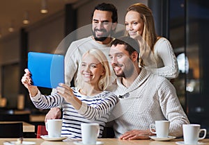 Happy friends with tablet pc taking selfie at cafe