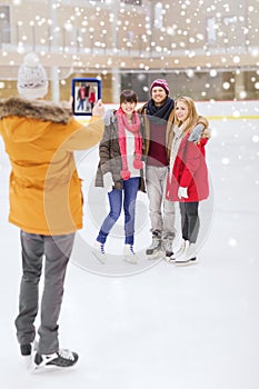 Happy friends taking photo on skating rink