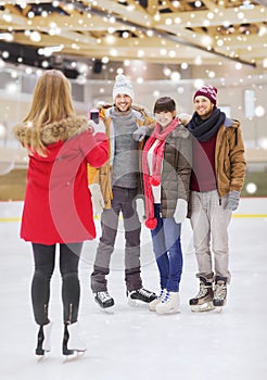 Happy friends taking photo on skating rink