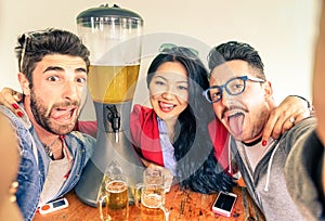 Happy friends taking selfie with funny tongue out and beer tower