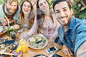 Happy friends taking selfie with mobile smartphone while lunching in coffee brunch restaurant