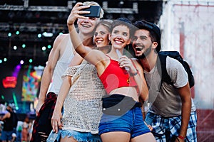 Happy friends taking selfie at music festival