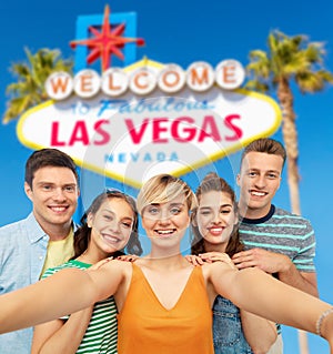 Happy friends taking selfie over las vegas sign