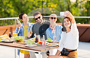 Happy friends taking selfie at rooftop party