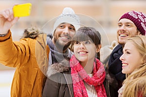 Happy friends taking selfie on skating rink