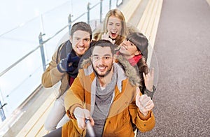 Happy friends taking selfie on skating rink