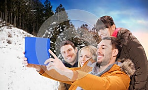 Happy friends taking selfie by tablet pc in winter