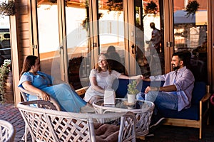 The happy friends are talking and laughing in a cafe terrace