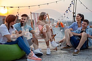 Happy friends toasting with drinks at a rooftop party