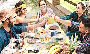 Happy friends toasting healthy fruit juice at countryside picnic - Young family concept with alternative people having fun