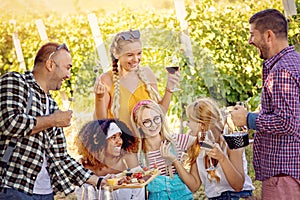 Happy friends in vineyard tasting wine - Young multiracial people enjoying time together outside at countryside photo