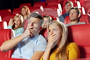 Happy friends watching horror movie in theater