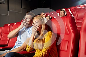 Happy friends watching horror movie in theater