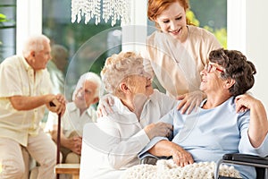 Happy friendship in old age. Tender caregiver standing behind se