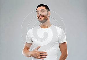 Happy full man touching tummy over gray background photo
