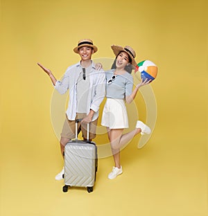 Happy fun Asian couple traveler with suitcase and beach ball isolated on yellow background, Tourist girl having cheerful holiday