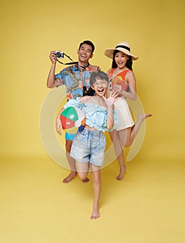 Happy fun asian family vacation portrait. Father, mother and daughters enjoying summer beach isolated on yellow studio background