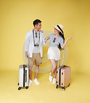 Happy fun Asian tourist couple with suitcase journey travel in summer isolated on yellow background