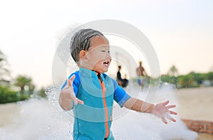 Happy and fun of little asian baby boy in swimming suit having fun in foam party at the pool outdoor