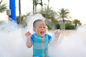 Happy and fun of little asian baby boy in swimming suit having fun in foam party at the pool outdoor