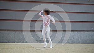 Happy funky young woman dancing jumping on urban wall background, slow motion.