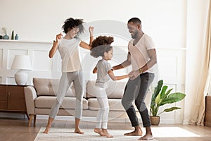 Happy funny active african family with daughter dancing at home photo