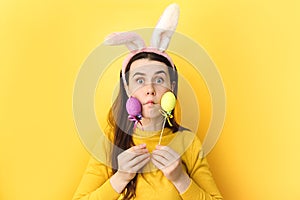 Happy funny beautiful smiling young woman 20s wearing rabbit ears holding colorful Easter eggs, playful brunette female with bunny