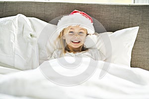 A happy funny child girl in bed on Christmas morning