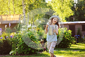 happy funny child girl in gardener hat playing with watering can