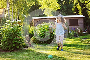 happy funny child girl in gardener hat playing with watering can