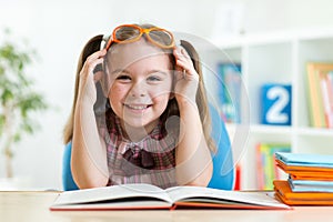 Happy funny child girl in glasses reading a book