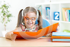 Happy funny child girl in glasses reading a book