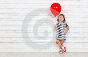 Happy funny child girl with red ball near an brick wall