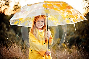 Happy funny child with umbrella under the autumn shower.