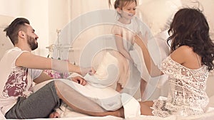 Happy funny family having a pillow fight in bed