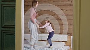 Happy funny family mother and child kid daughter dancing, jumping on bed, listening music at home