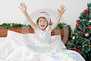 Happy funny girl haning fun on the bed on Christmas morning with New Year's decorations photo