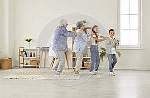 Happy, funny grandparents and children playing games, dancing and having fun together