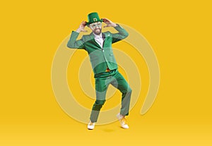 Happy funny guy in green suit and leprechaun hat having fun on Saint Patrick's Day