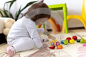 happy funny kid curly baby girl with educational toy blocks flowers. Children play at day care or preschool. Mess in