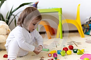 happy funny kid curly baby girl with educational toy blocks flowers. Children play at day care or preschool. Mess in