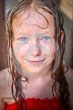 Happy funny little blone girl with wet hair after rain in a summer or spring day