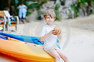 Little kid boy drinking coconut juice on tropical beach