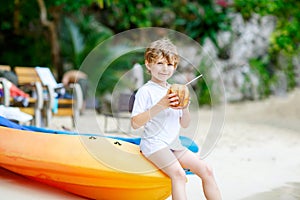 Little kid boy drinking coconut juice on tropical beach