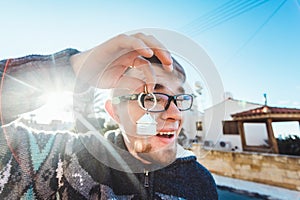 Happy funny man holds house keys on house shaped keychain in front of a new home