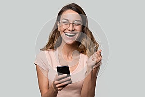 Happy funny millennial woman celebrating mobile win isolated on background