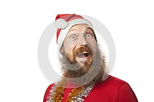 Happy funny santa claus with real beard and red hat and shirt making crazy face and smiling, looking and camera