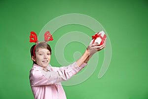 Happy funny teenager boy in red christmas deer costume in light shirt with gift