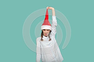 Happy funny teenager girl looking at camera with tongue out, pulling up her Santa Claus hat.